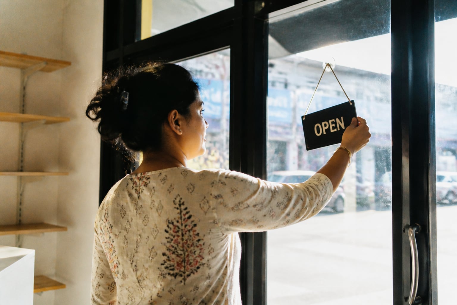 Shop owner flipping her door sign to OPEN on opening morning
